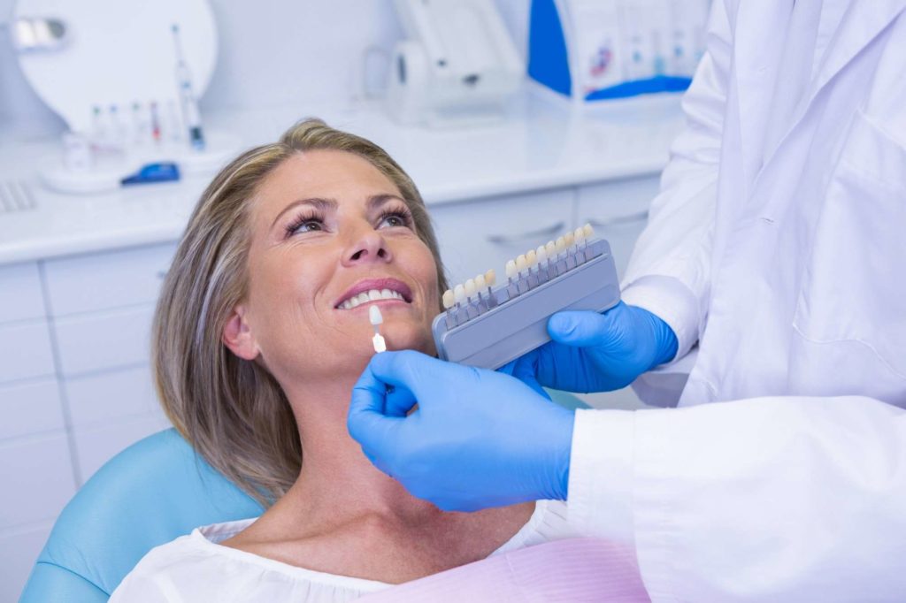 Blanqueamiento doctor holding tooth whitening equipment by patient