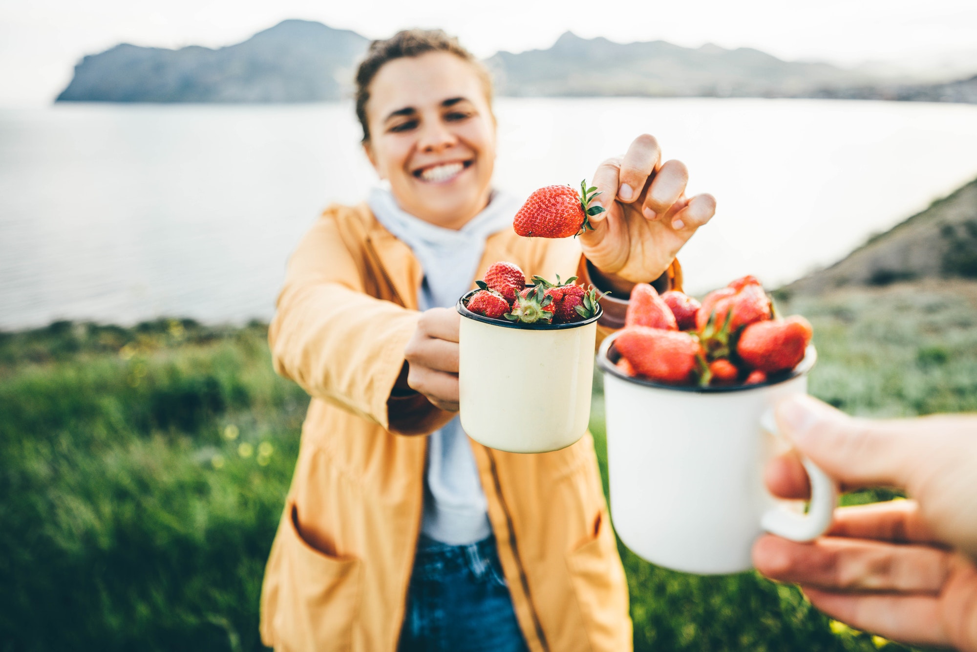 Couple smiling at camera while eating strawberries.