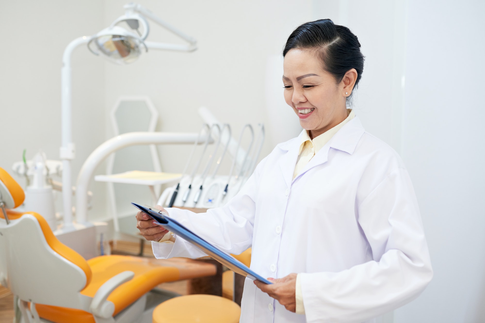 Smiling dentist reading clipboard in office
